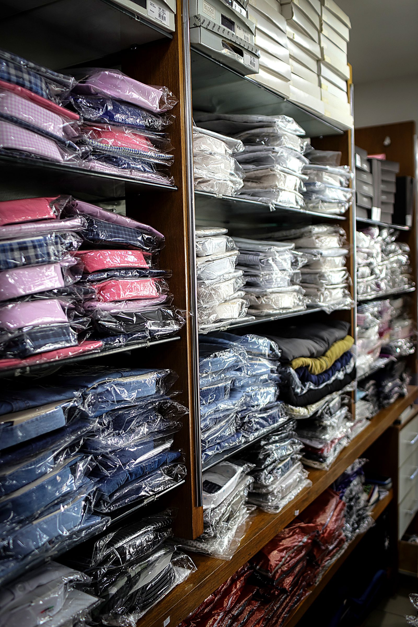 Acervo de camisas sociais dobradas em prateleiras de madeira