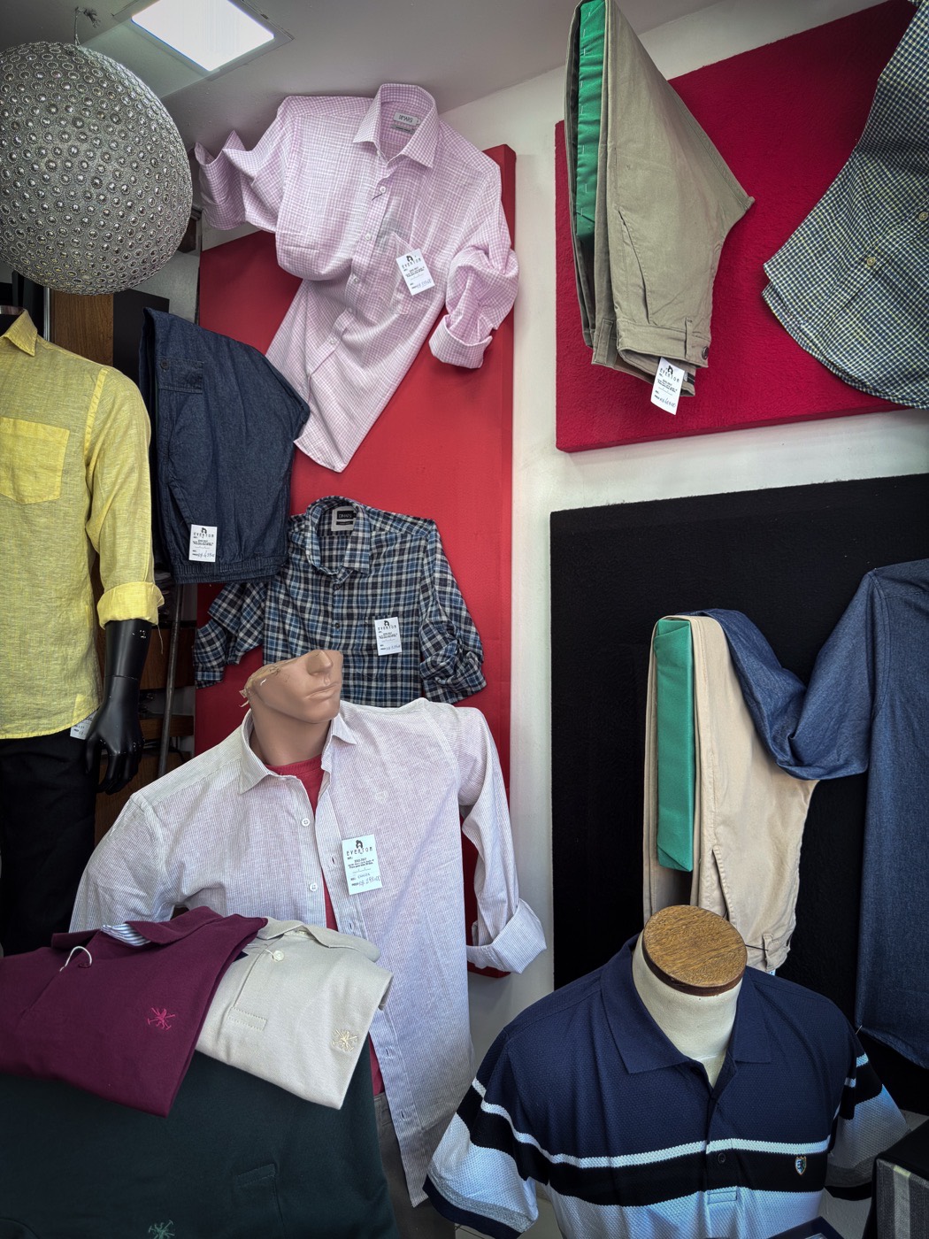 Manequins e painéis com camisas, calças e polos no interior da loja