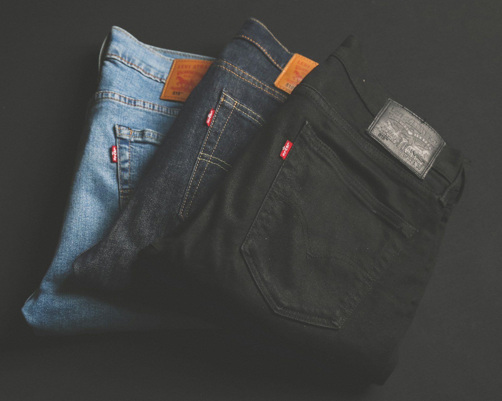 Três calças jeans clássicas dobradas, da lavagem clara à preta