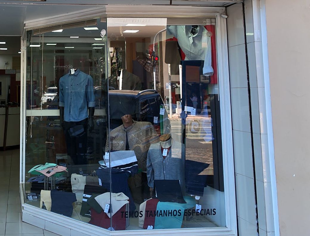 Vitrine da loja com manequins e o aviso: temos tamanhos especiais